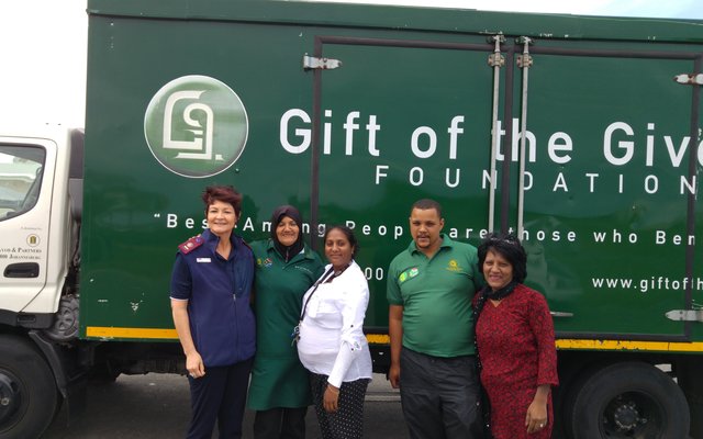 Gift of the Givers se beamptes, saam met Suster Dorothea Jacobs (links) en konst A Naidoo (3de van links) tydens die uitdeel van voedselpakkies